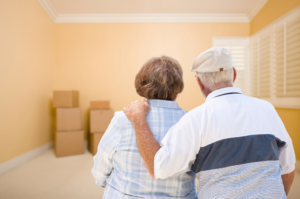Senior couple standing in bare room with stacked moving boxes