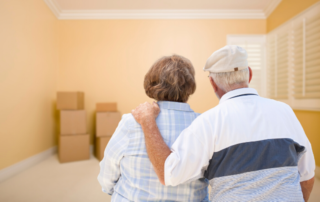 Senior couple standing in bare room with stacked moving boxes